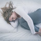 Desperate young woman curled up in bed