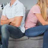 Couple sitting back to back after a fight on the sofa in sitting room at home