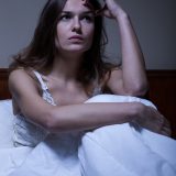 Thoughtful woman sitting in bed at night